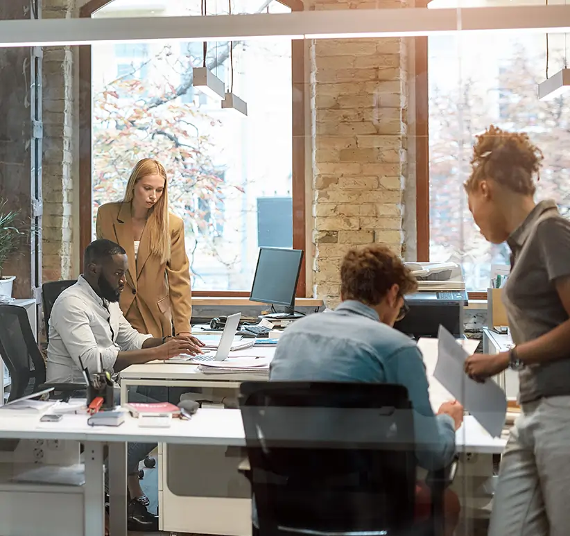 office workers looking at documents and computer screens in office setting